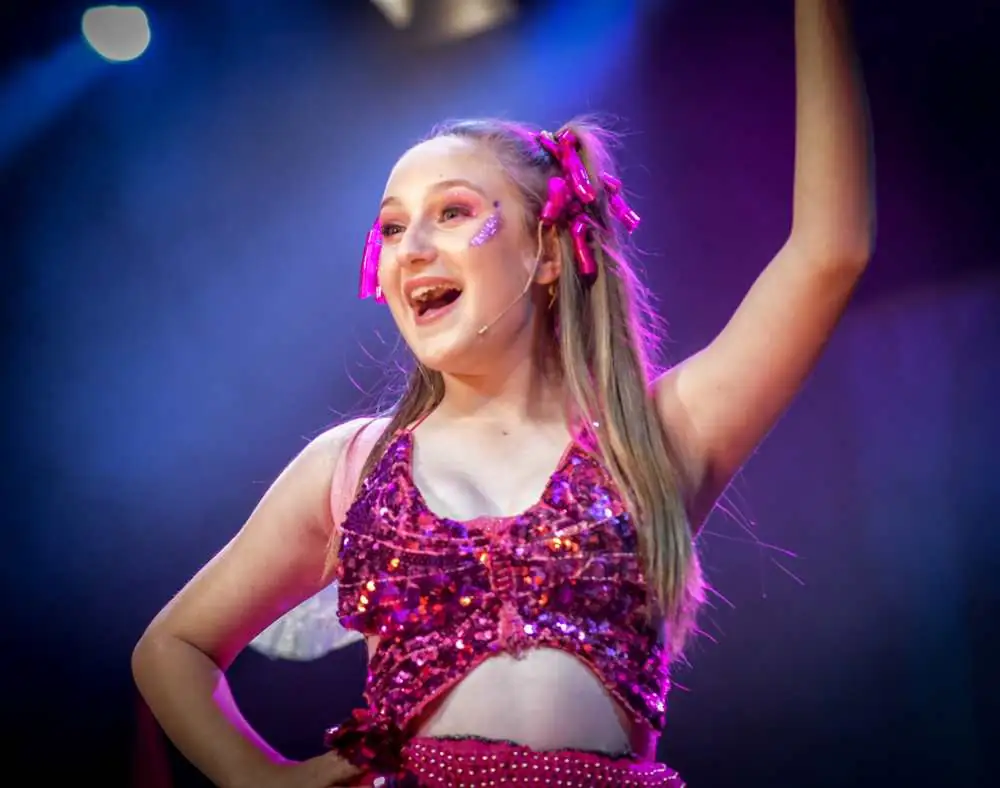 A performer in a sparkly pink top, all smiles