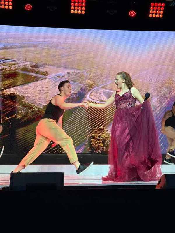 A dancer and singer in a burgundy gown in front of vineyards