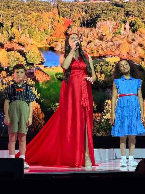 Three performers in front of a lake and autumn trees