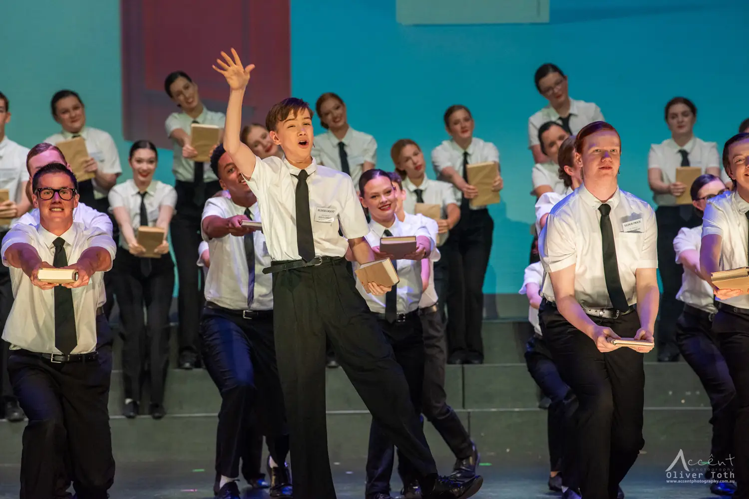 A senior Pelican company performing The Book of Mormon in white shirts and ties