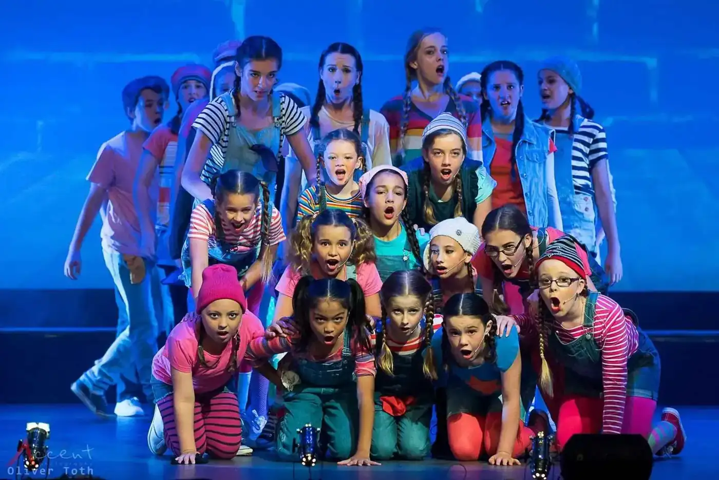 Young Pelican performers singing together on stage